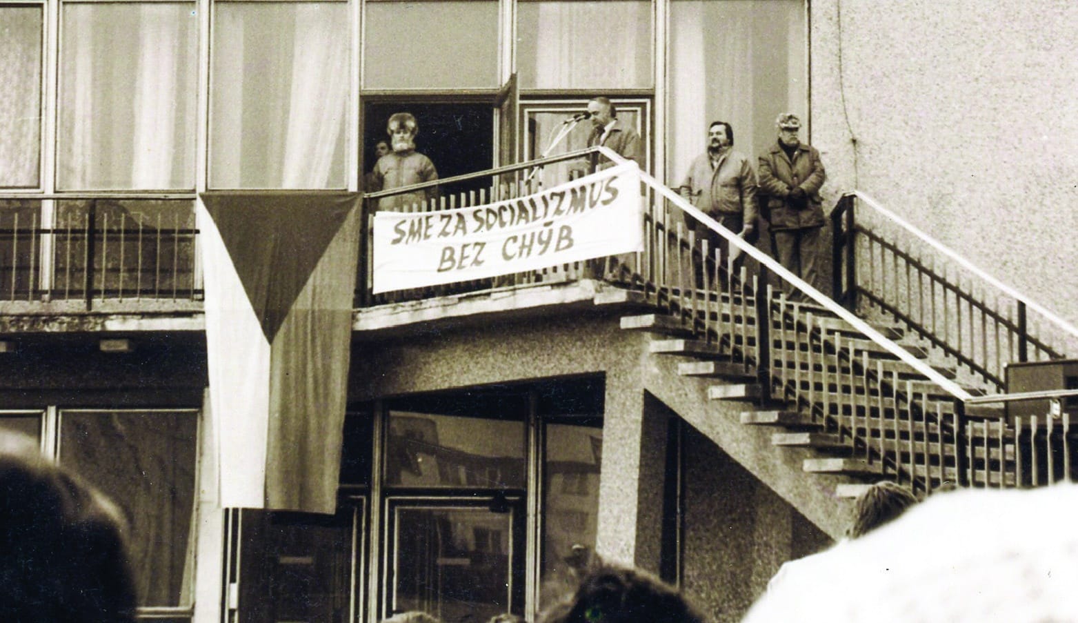 Balkón domu kultúry s transparentom „Sme za socializmus bez chýb“ a štátnou vlajkou (červeno tónovaná fotografia)